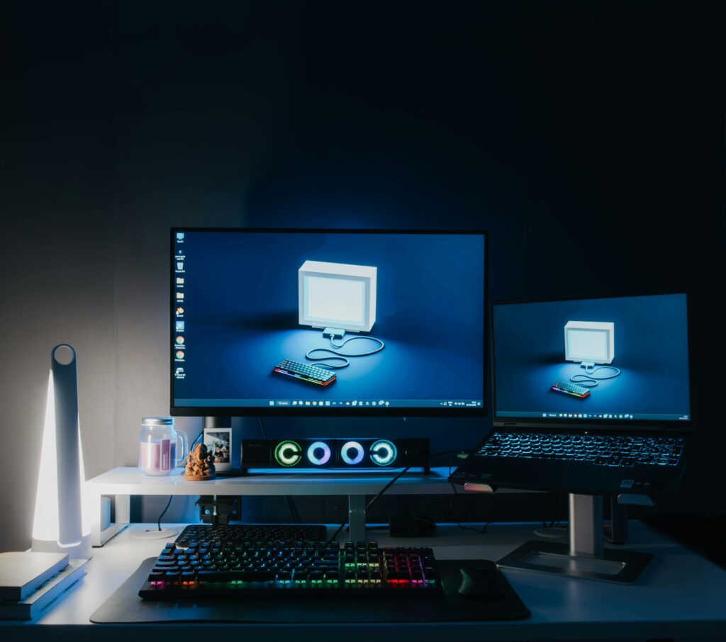 A sleek home office setup featuring dual monitors, RGB lighting, and tech gadgets, ideal for gaming or work.