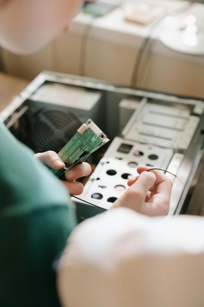 Close-up of hands installing RAM into an open PC case, depicting computer repair and maintenance.