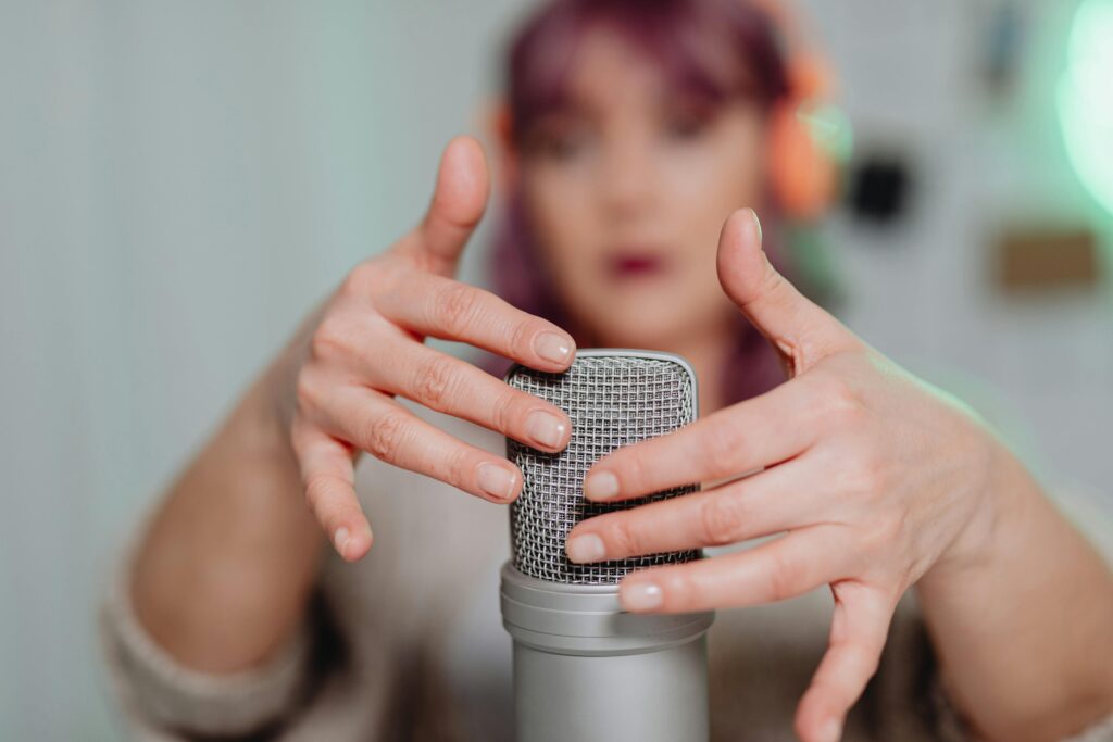 A woman gently touching a microphone during an ASMR recording session indoors.