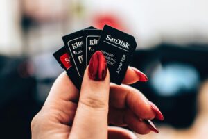 A close-up image of a woman's hand holding multiple microSD memory cards with red nails.