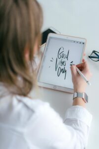 Person using a tablet and stylus to write 'Good Vibes Only' in an artistic style.