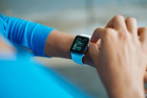 Person interacting with a smartwatch, showing a fitness application on the screen.