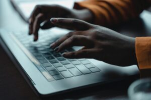 Close-up of hands typing on a laptop keyboard, capturing a moment of focused work.