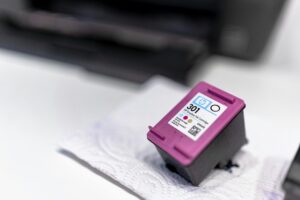 A close-up of a printer ink cartridge resting on a paper towel, showcasing its design and details.